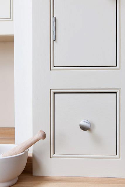 Close-up of a hand-painted shaker drawer front with a polished silver knob